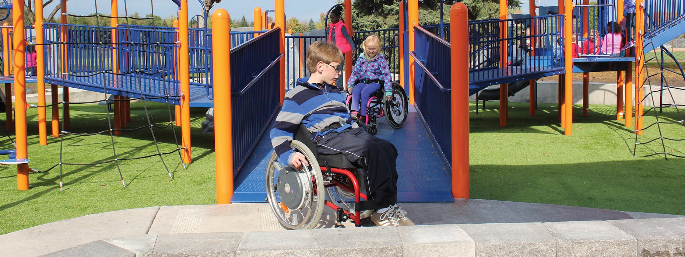 Children in wheelchairs on playground.