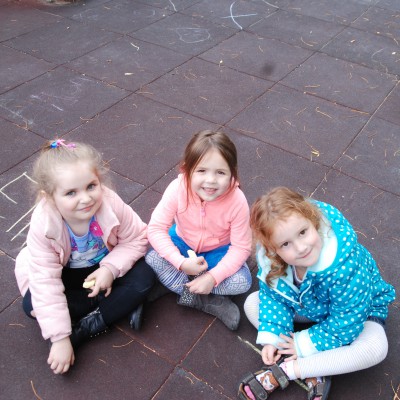 Three children playing on sidewalk.