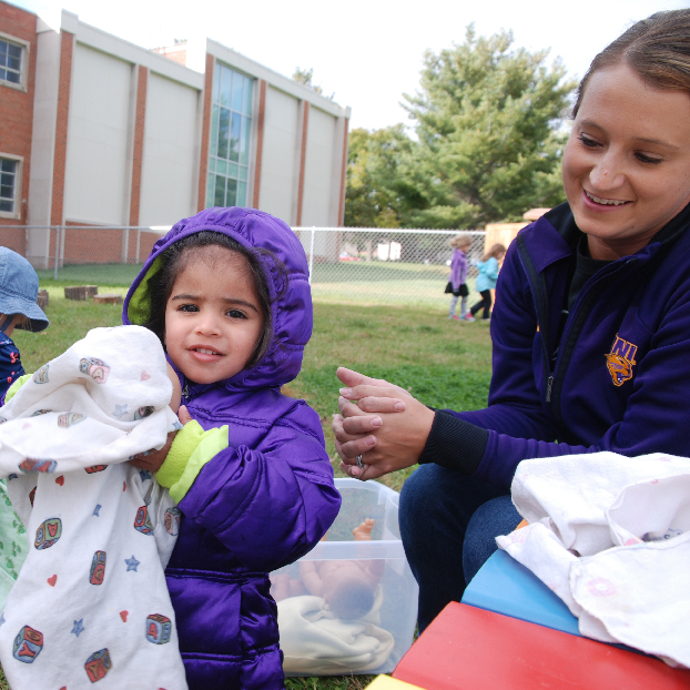 Child playing with a blanket outside.