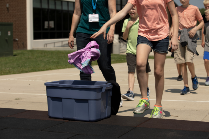 Children throwing jackets in a bin.